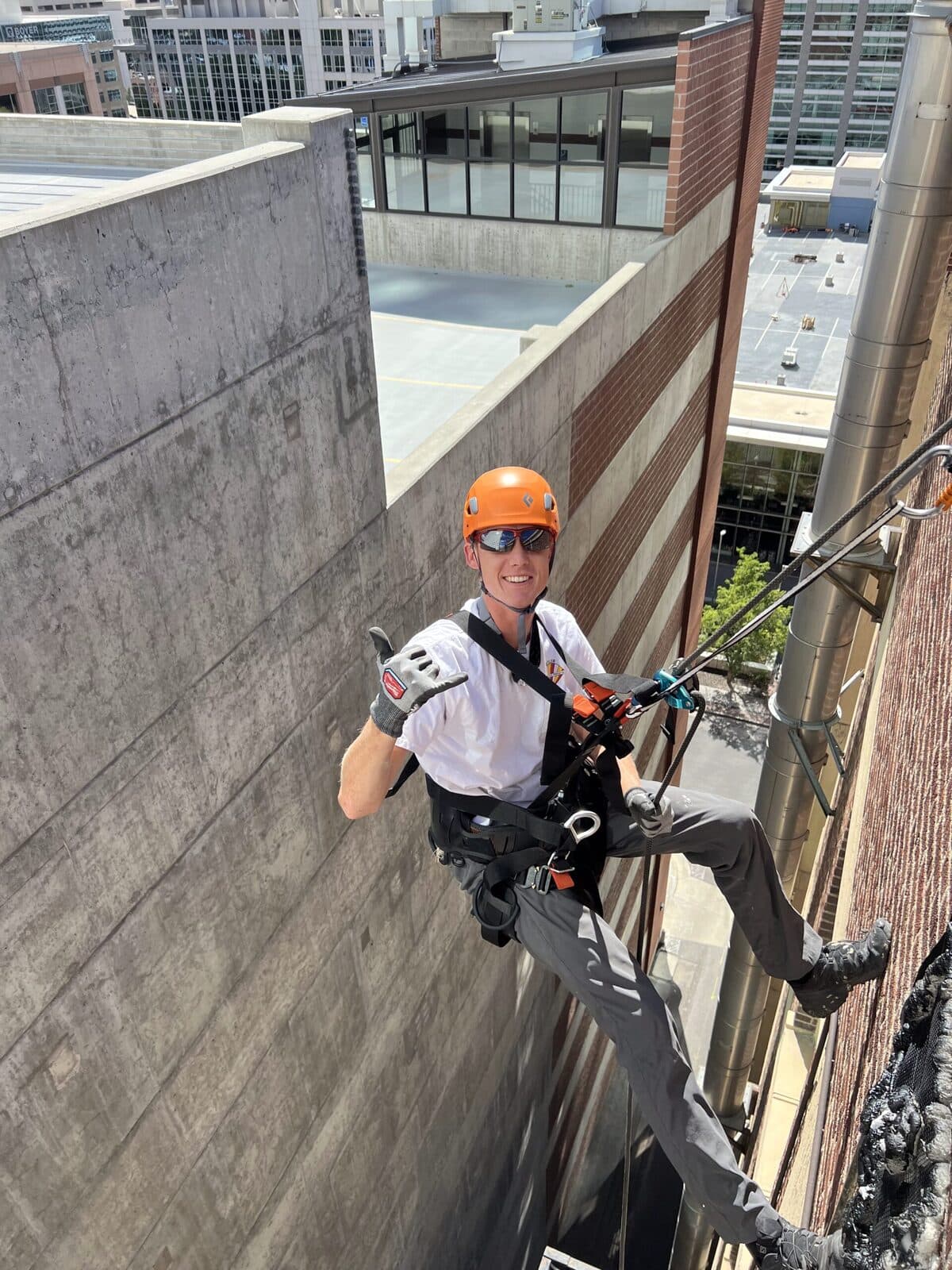 Technician in climbing gear giving a thumbs up during exterior exclusion work